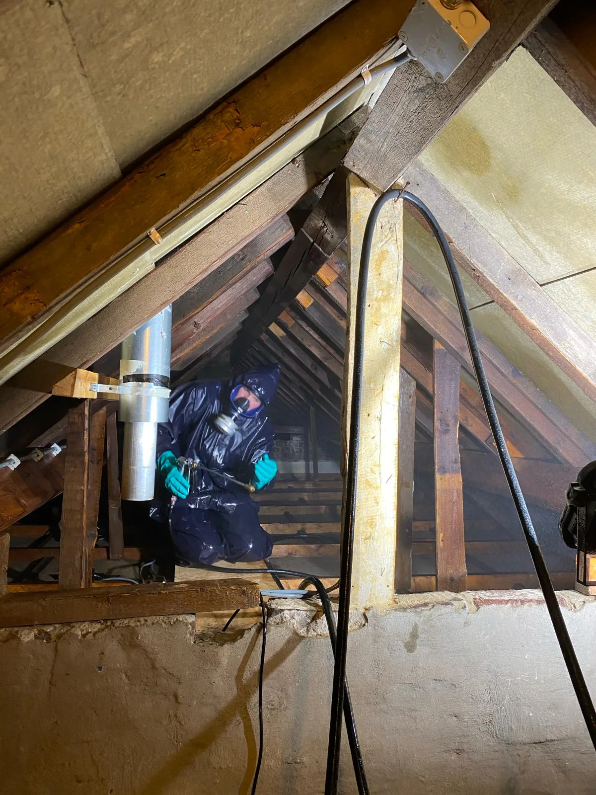 Specialist in beschermende kleding behandelt hout in een kapconstructie