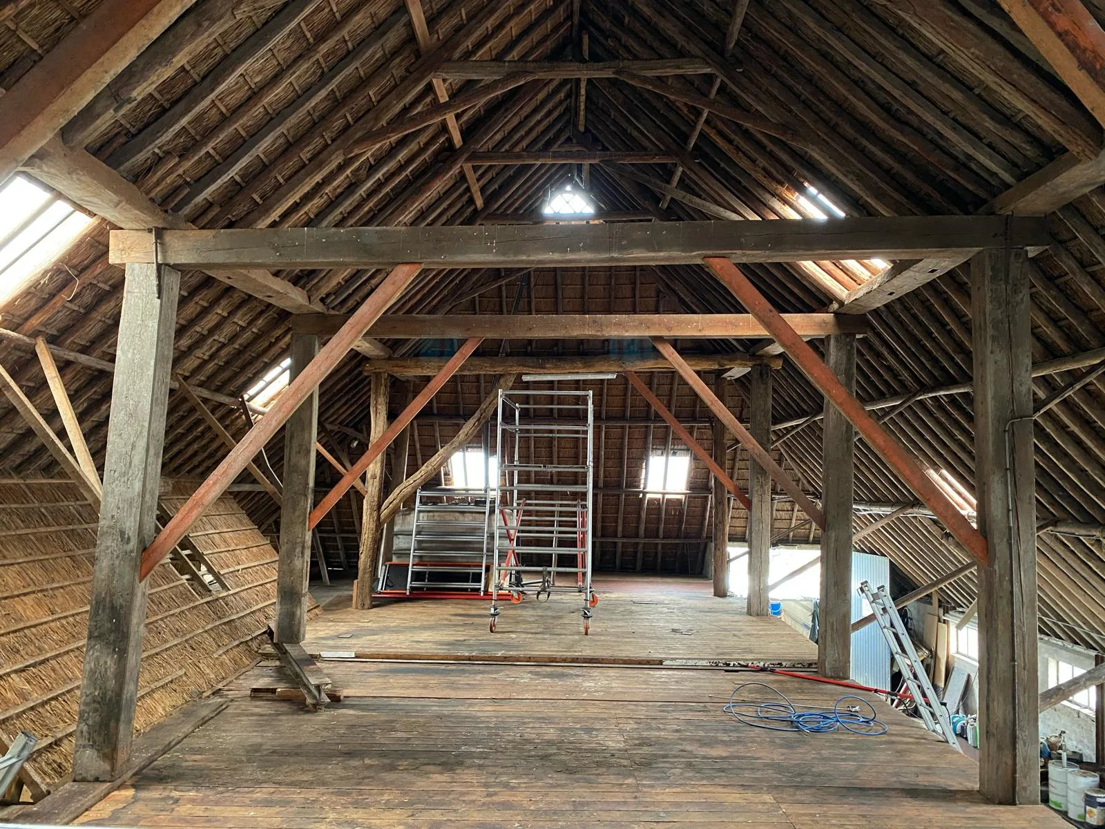 Grote houten kapconstructie in een oude schuur met een steiger voor inspectie en behandeling